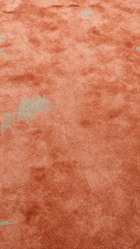 closeup of a terracotta rug texture with subtle sage accents