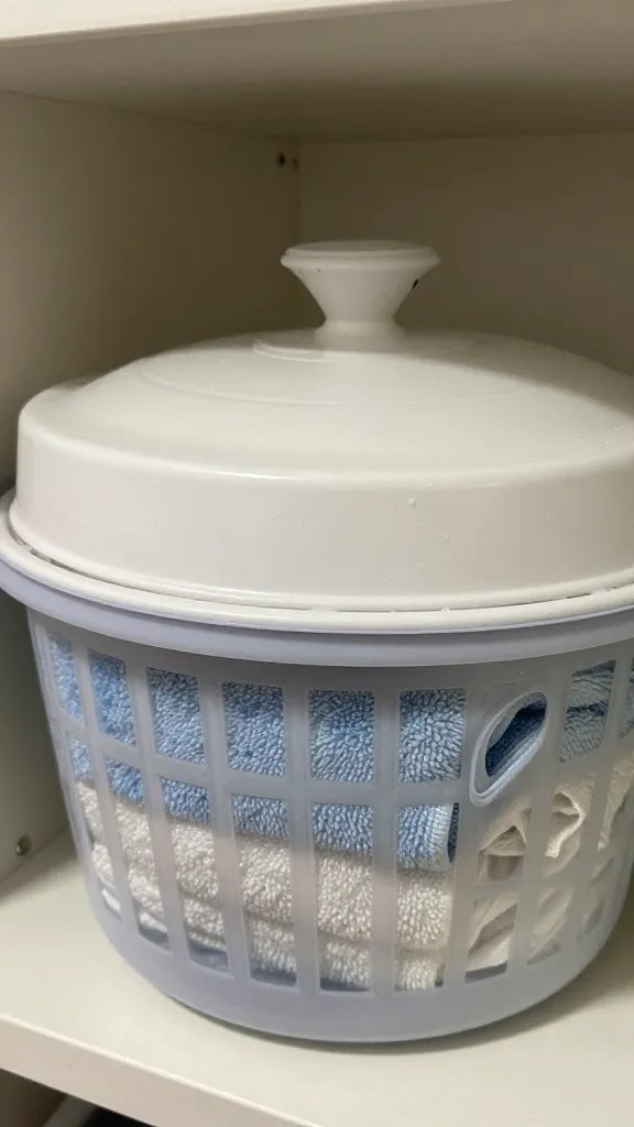 closeup of a lidded basket hiding towels on a shelf
