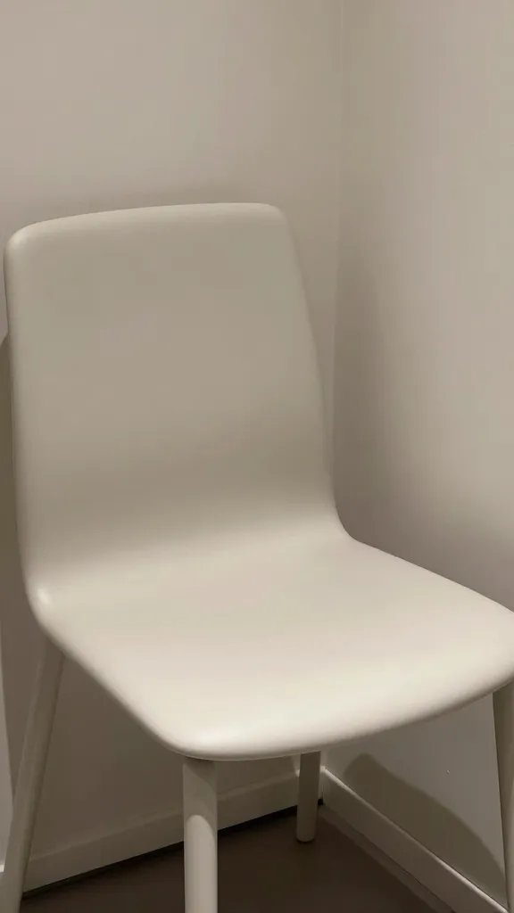 Closeup of light-colored modern chair in minimalist corner nook