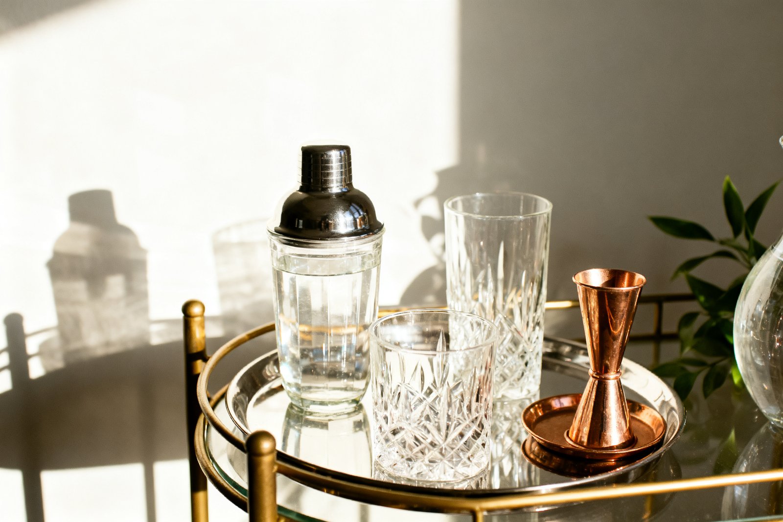 Close-up of glassware and a small tray on a styled bar cart