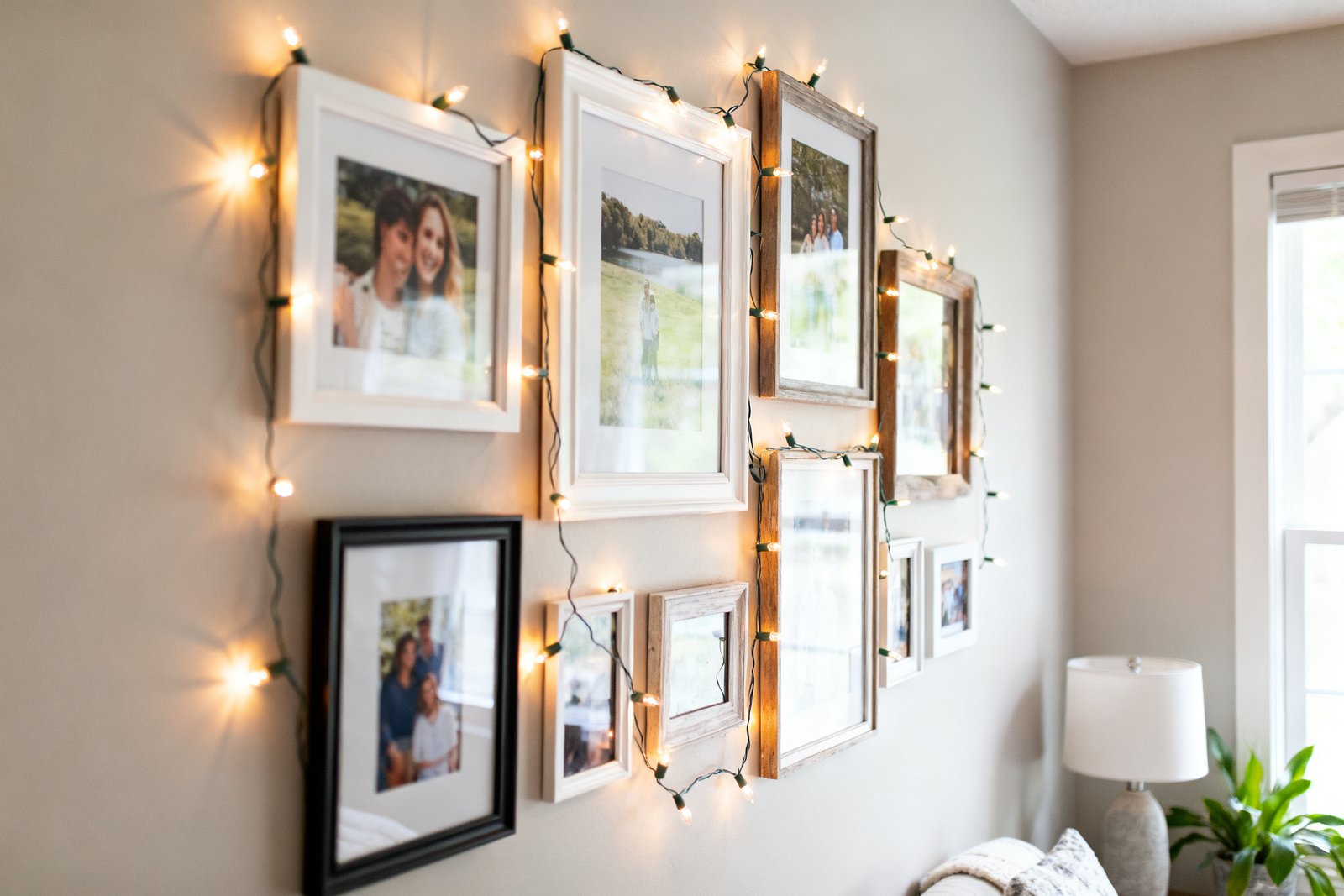 A budget DIY photo wall with framed photos and warm string lights in a cozy room