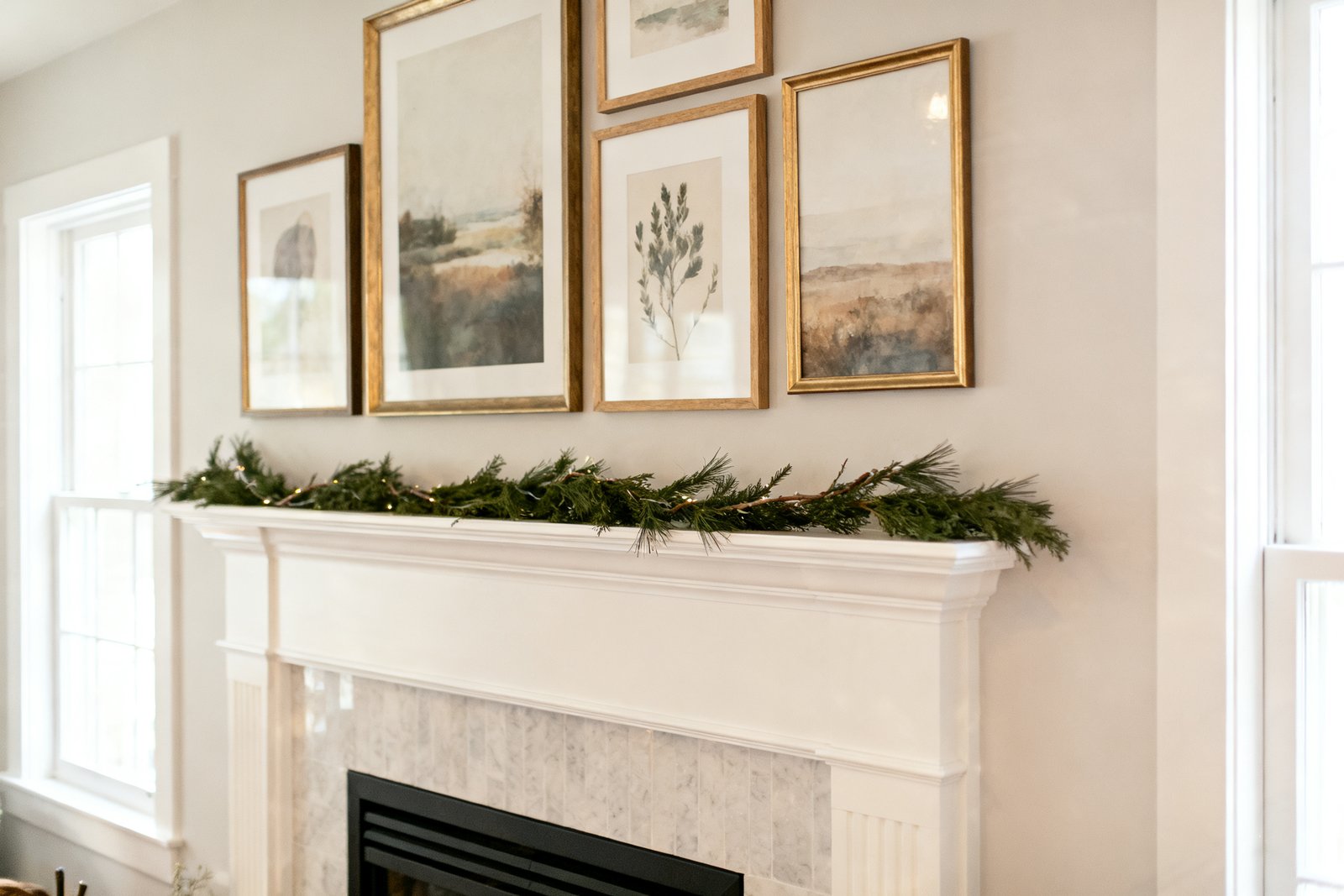Framed art and a simple garland decorating a fireplace wall