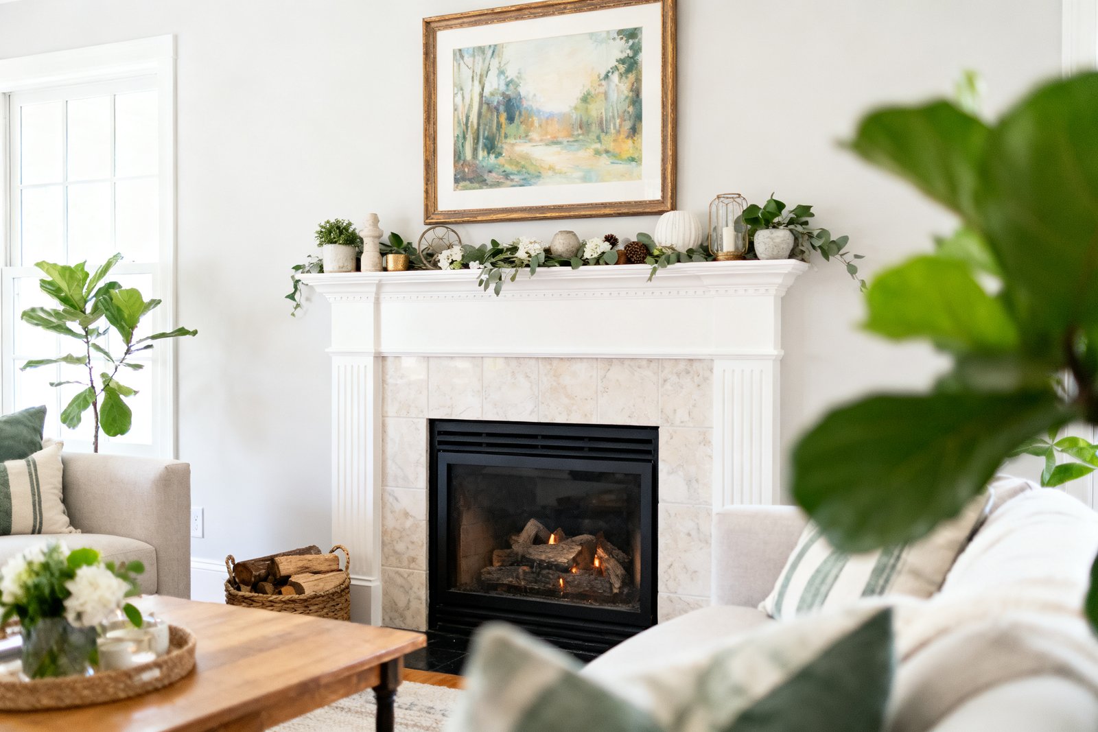 A budget-decorated fireplace with a styled hearth, framed art above, and greenery, cozy living room