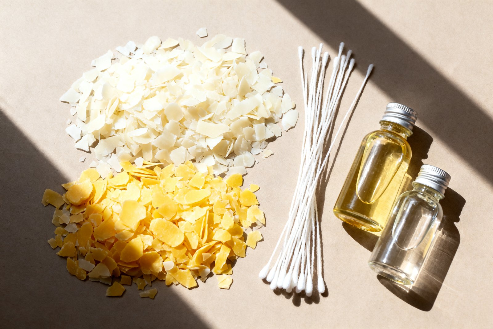 A flat lay of candle-making supplies: wax flakes, wicks, and oils