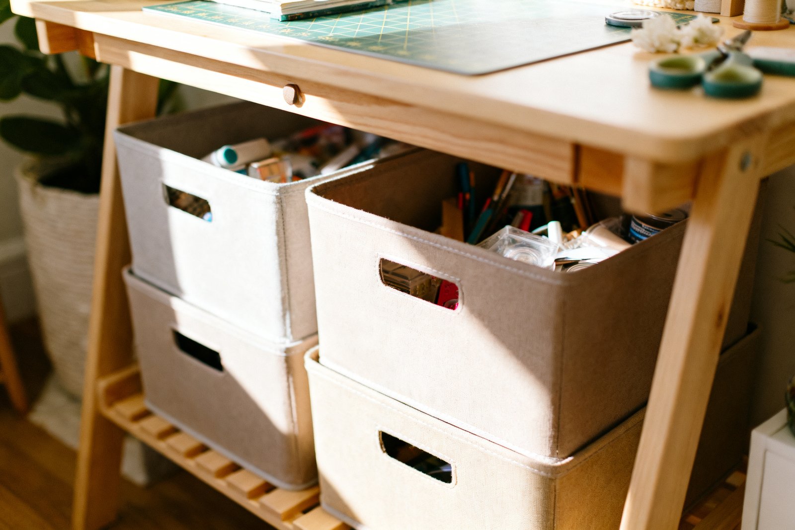 Stackable bins with labels tucked under a small craft desk